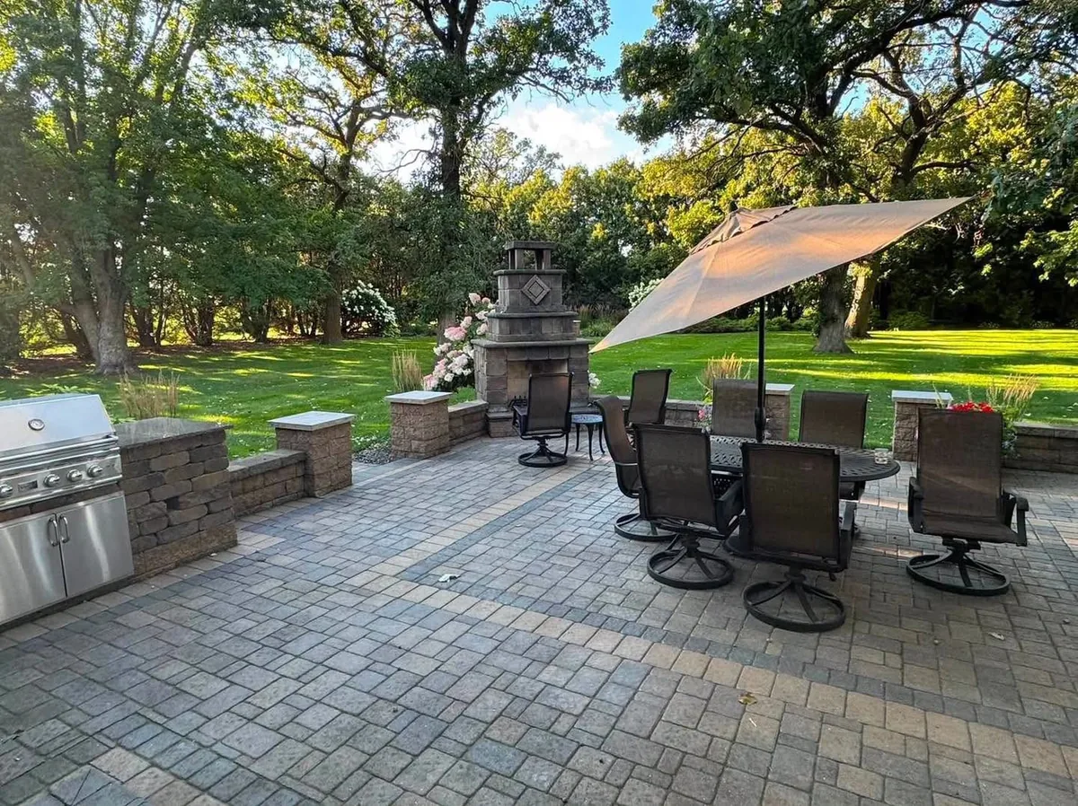 Outdoor kitchen, stone fireplace, and paver dining patio in Southern Minnesota